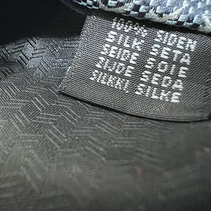 Close-up of a textured black cap with brand name on a dark background