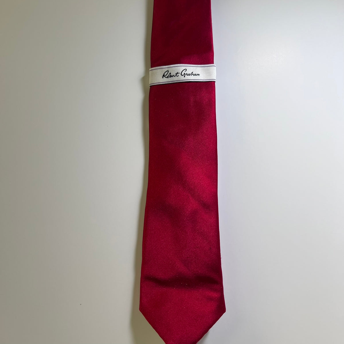 A red silk necktie with a white band label featuring the script brand name 'Robert Guichan', displayed against a plain light gray background.