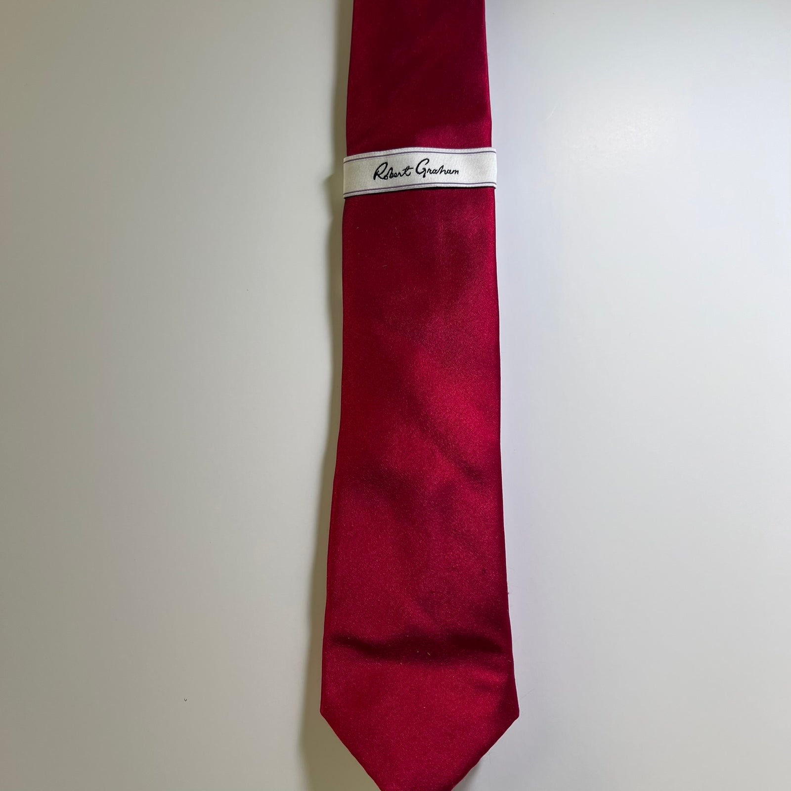 A red silk necktie with a white band label featuring the script brand name 'Robert Guichan', displayed against a plain light gray background.