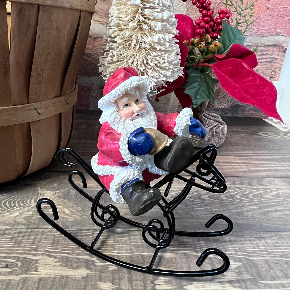 Decorative figure of Santa Claus on a sleigh with Christmas decorations in the background.