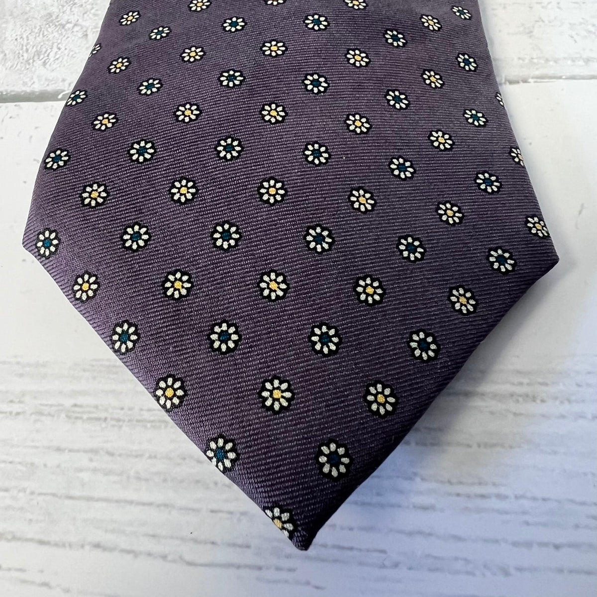 purple tie with white floral pattern on a light wooden surface