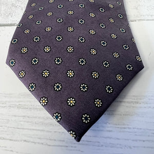 purple tie with white floral pattern on a light wooden surface