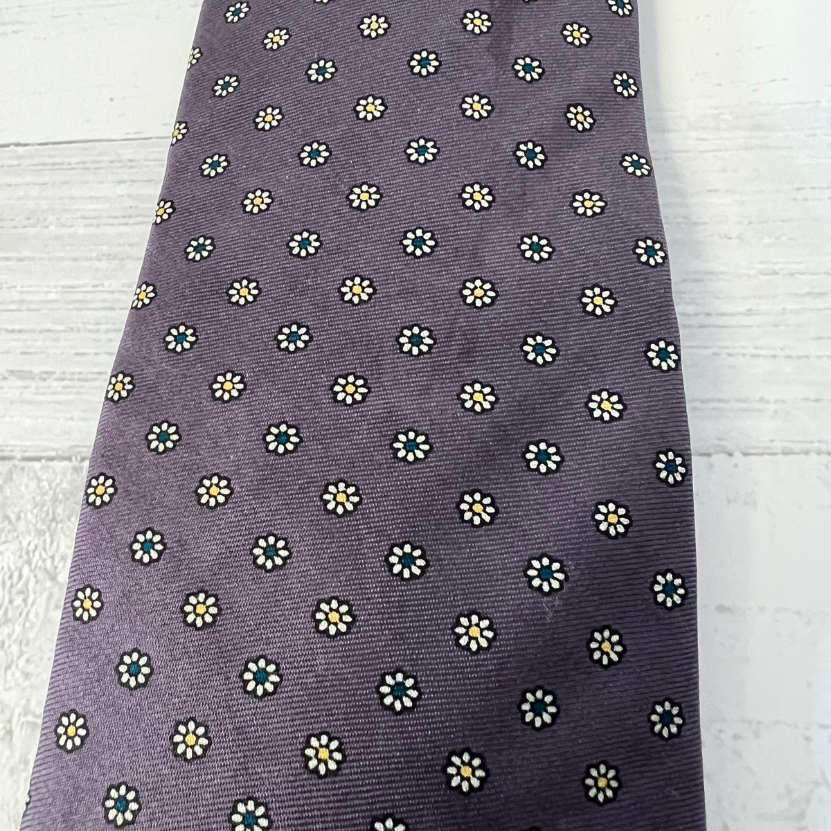 purple tie with small white floral pattern on a light wooden surface