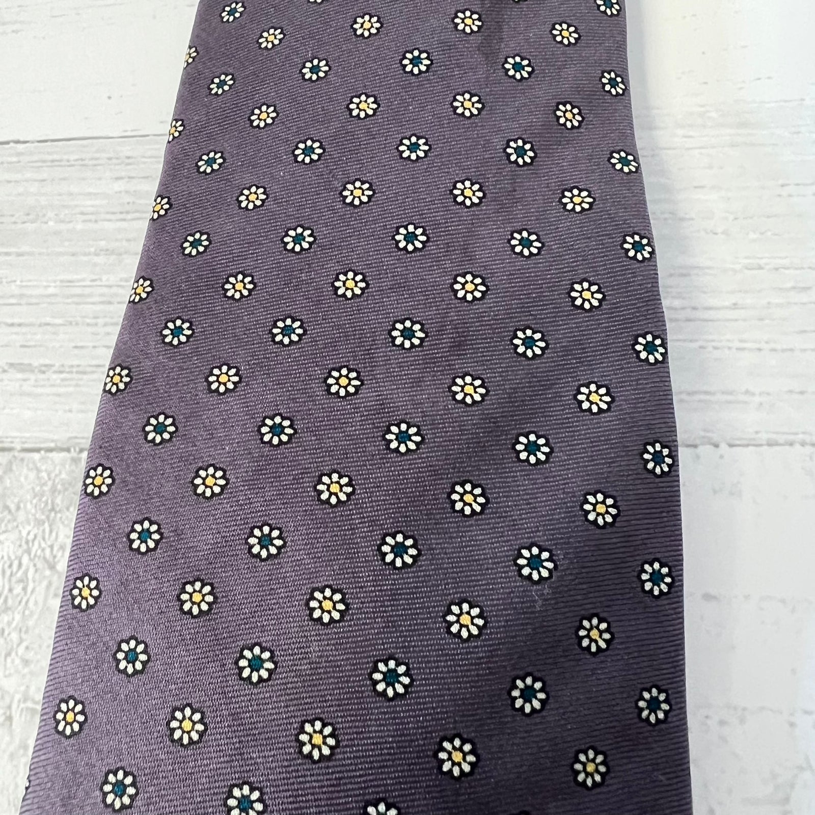 purple tie with small white floral pattern on a light wooden surface