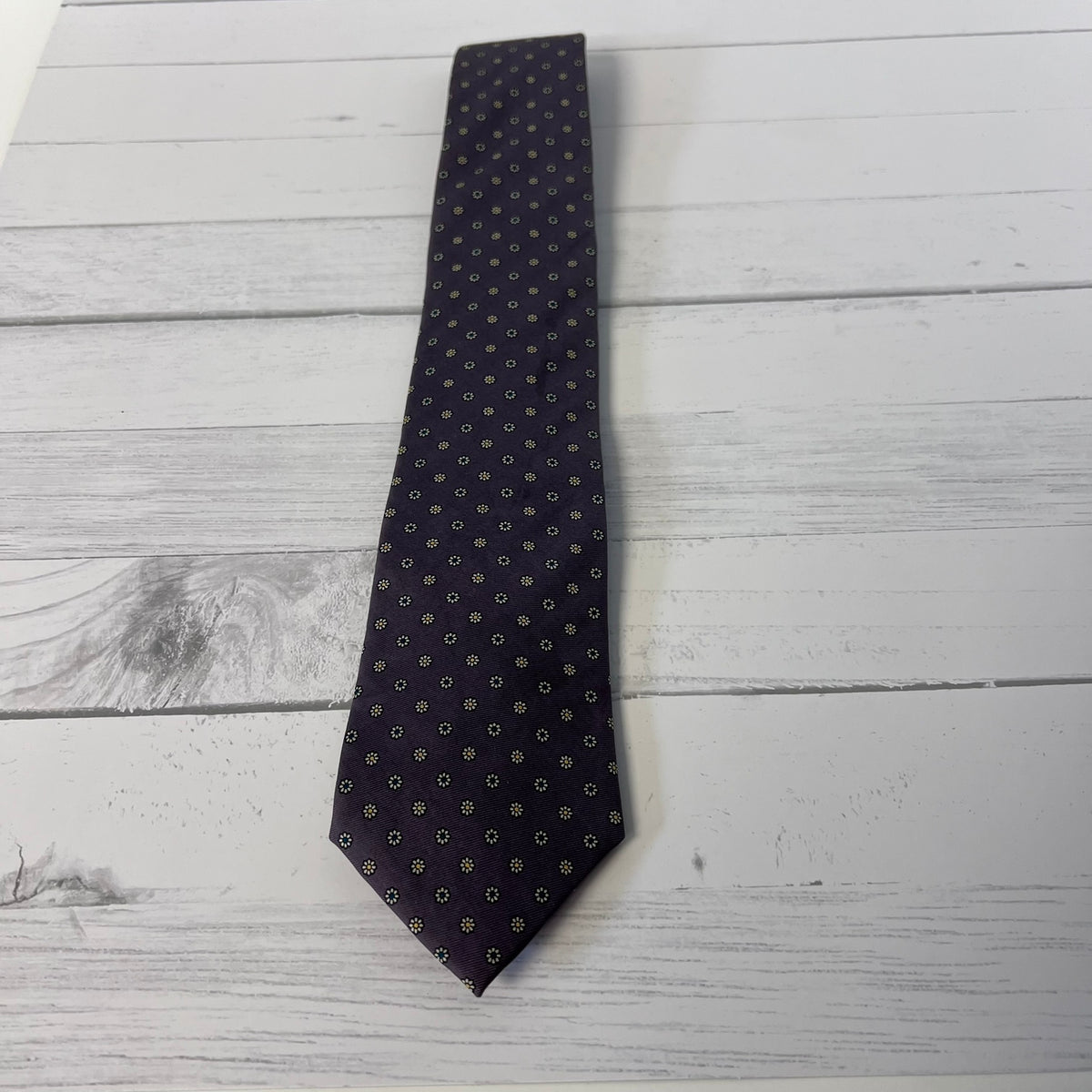 Purple patterned tie on a light wooden surface