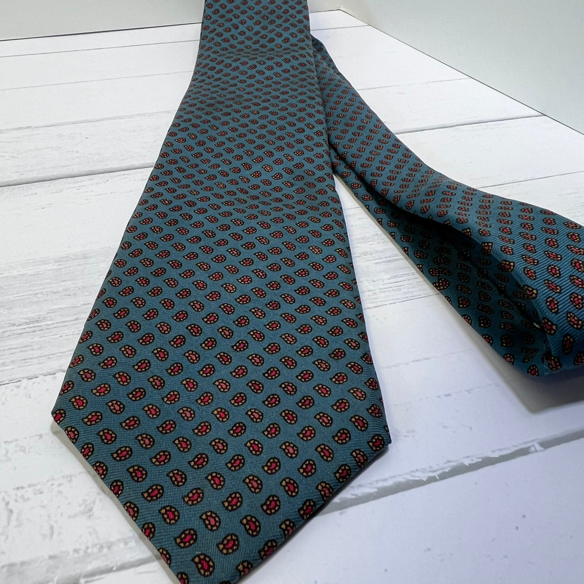 Green patterned tie on a white wooden surface