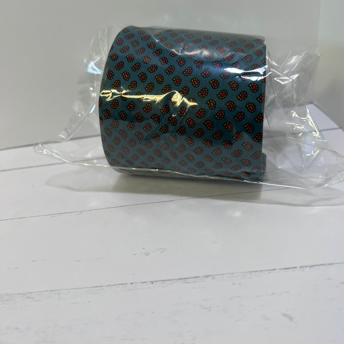 Blue tie with red pattern in clear packaging on a white surface