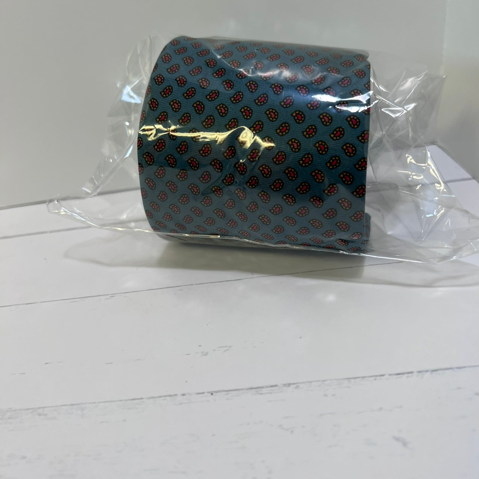 Blue tie with red pattern in clear packaging on a white surface