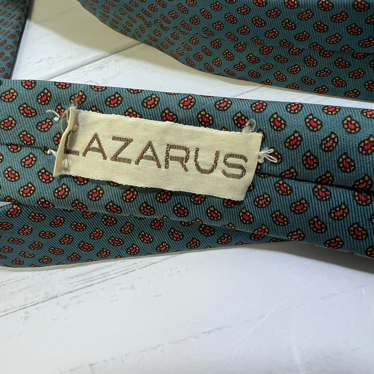 Folded patterned tie with 'LAZARUS' label on a white surface