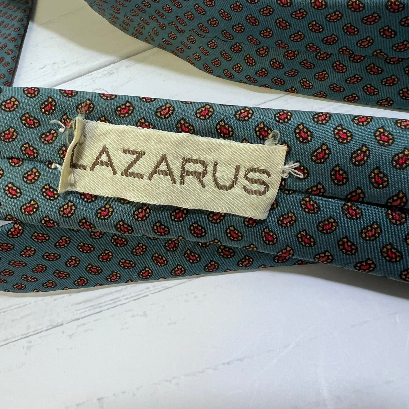 Folded patterned tie with 'LAZARUS' label on a white surface