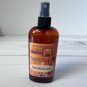 Brown spray bottle labeled 'Chickenmash Farm Sandalwood' on a white wooden surface.