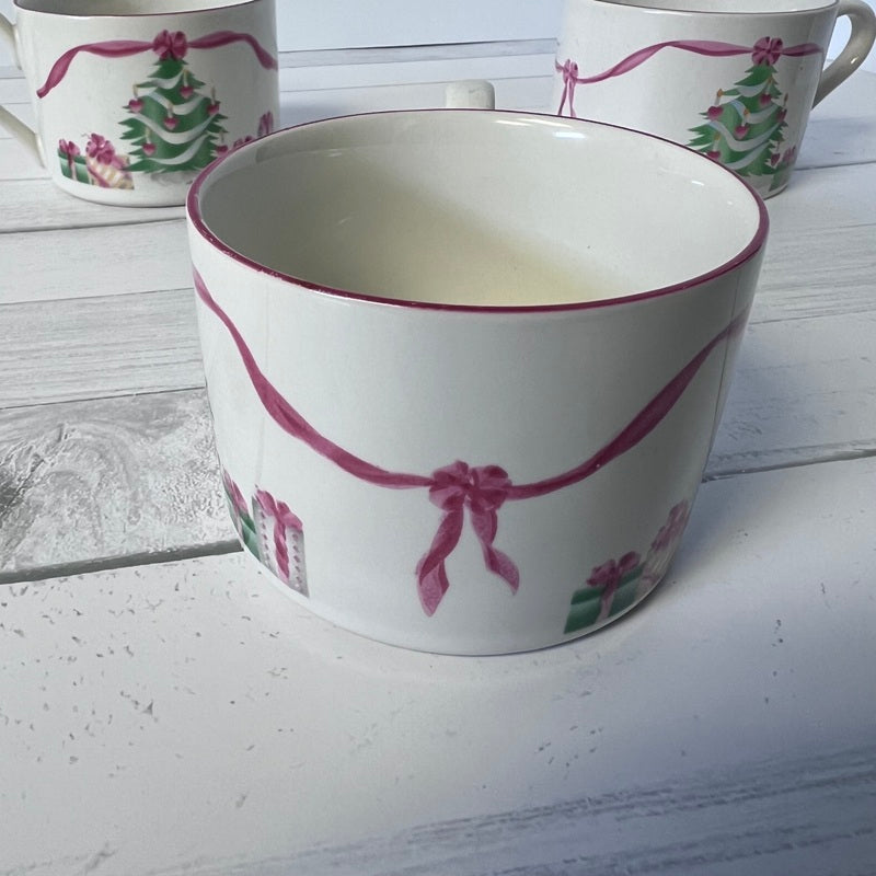 White mug with pink ribbon design on a wooden surface