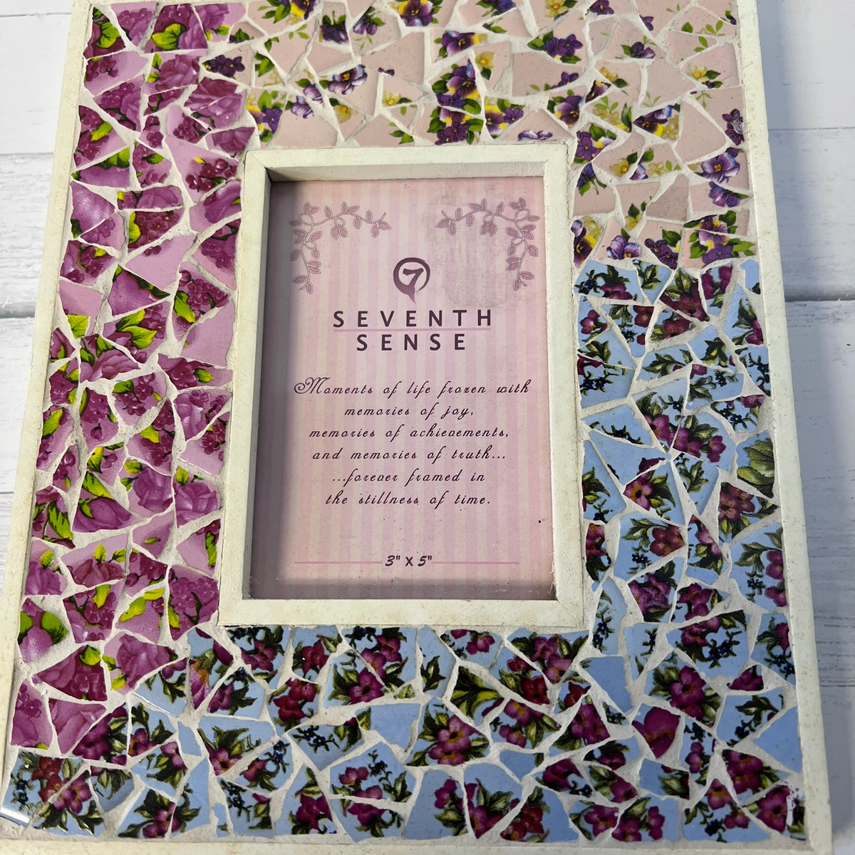 A square mosaic picture frame with a floral tile pattern in purple, pink, green, and blue, featuring a central light wood frame with a 'Seventh Sense' memorial insert.