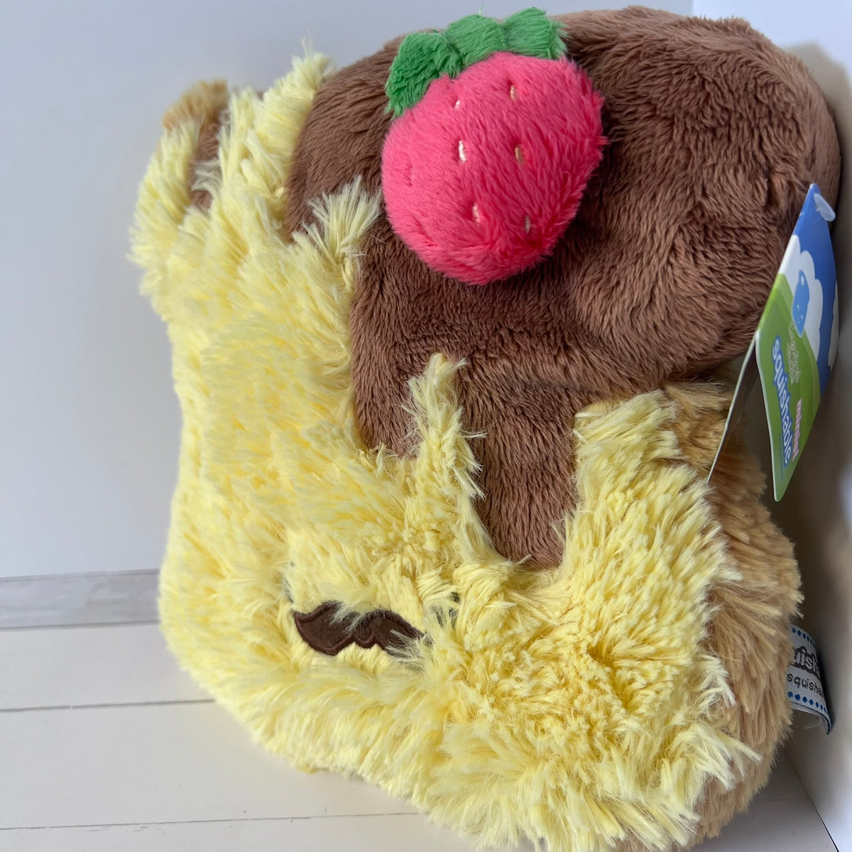 Plush toy resembling a piece of cake with a strawberry on a white background