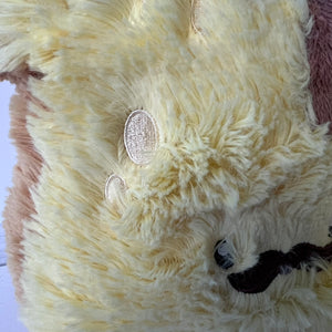 Close-up of a fluffy cream-colored animal toy with pink ears on a white background