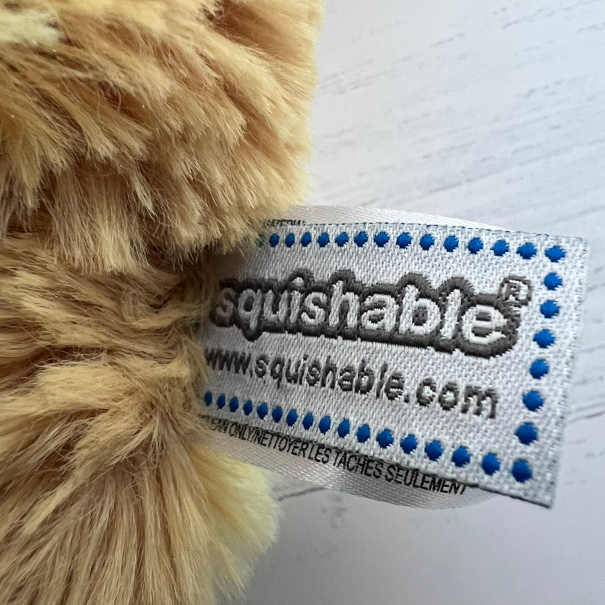 Close-up of a 'squishable' label on a plush toy with a white background