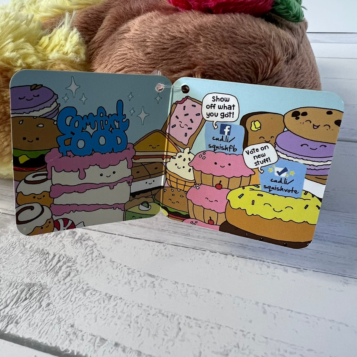 Two colorful card designs with cartoon food characters on a wooden surface.