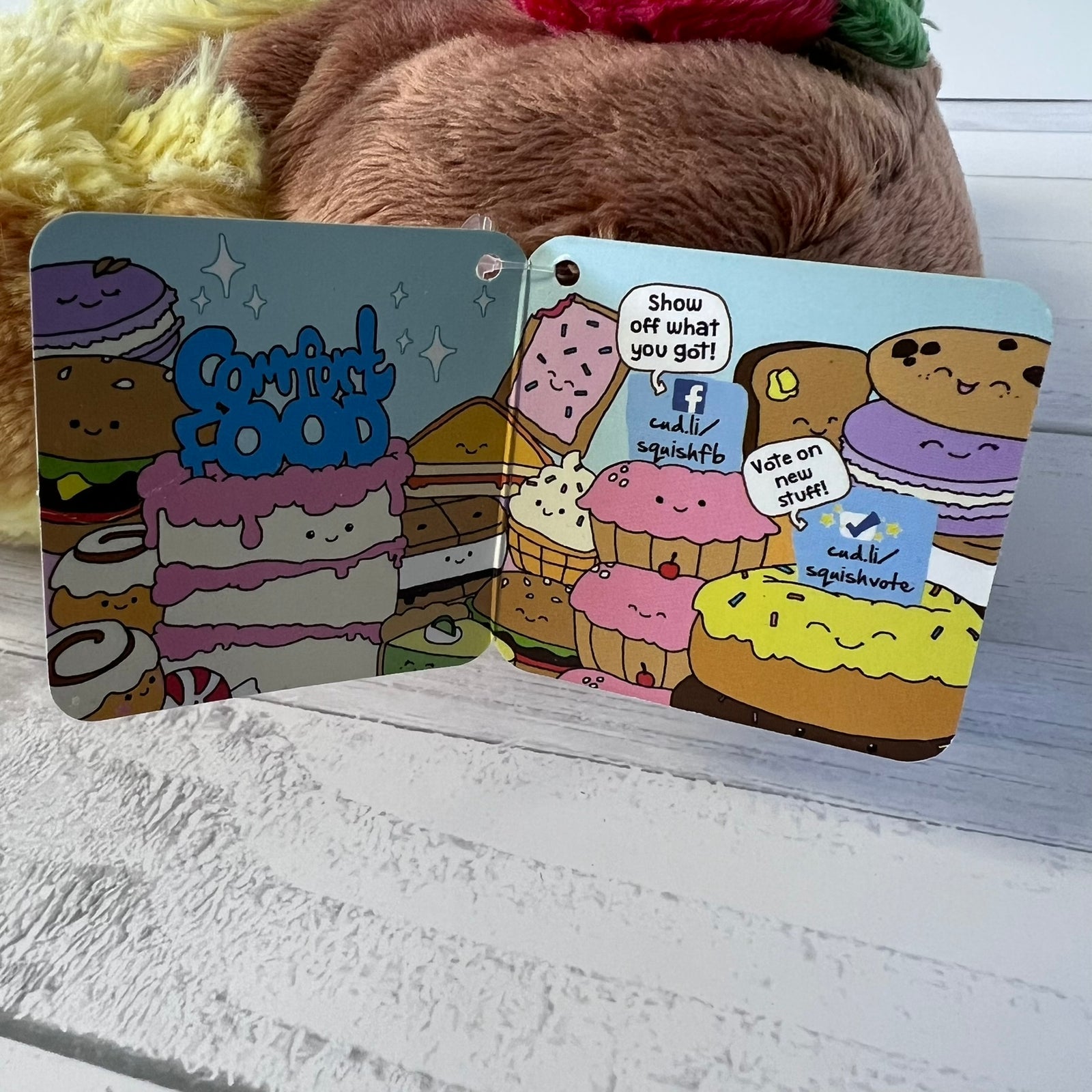 Two colorful card designs with cartoon food characters on a wooden surface.