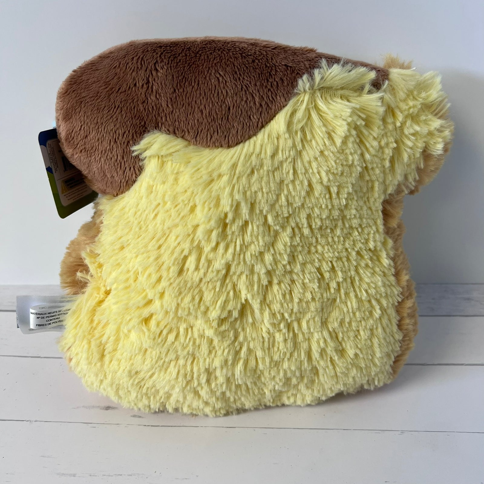 Plush toy resembling a character with a brown top and yellow bottom on a white surface.