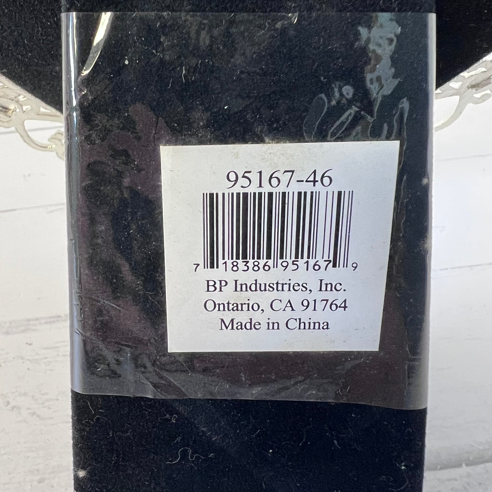 A close-up of the back of a black rectangular product wrapped in clear plastic, showing a white label with a barcode and text reading '95167-46', 'BP Industries, Inc. Ontario, CA 91764', and 'Made in China'.