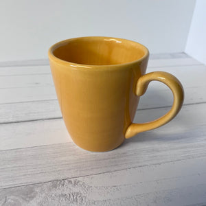 Yellow mug on a wooden surface with a white background