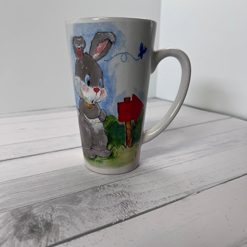 White mug with a painted rabbit design on a wooden surface