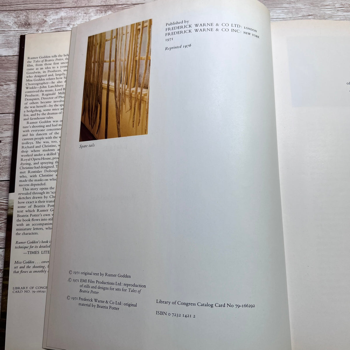 An open book showing printed text and a small inset photograph of wooden blinds, photographed on a light wood surface.