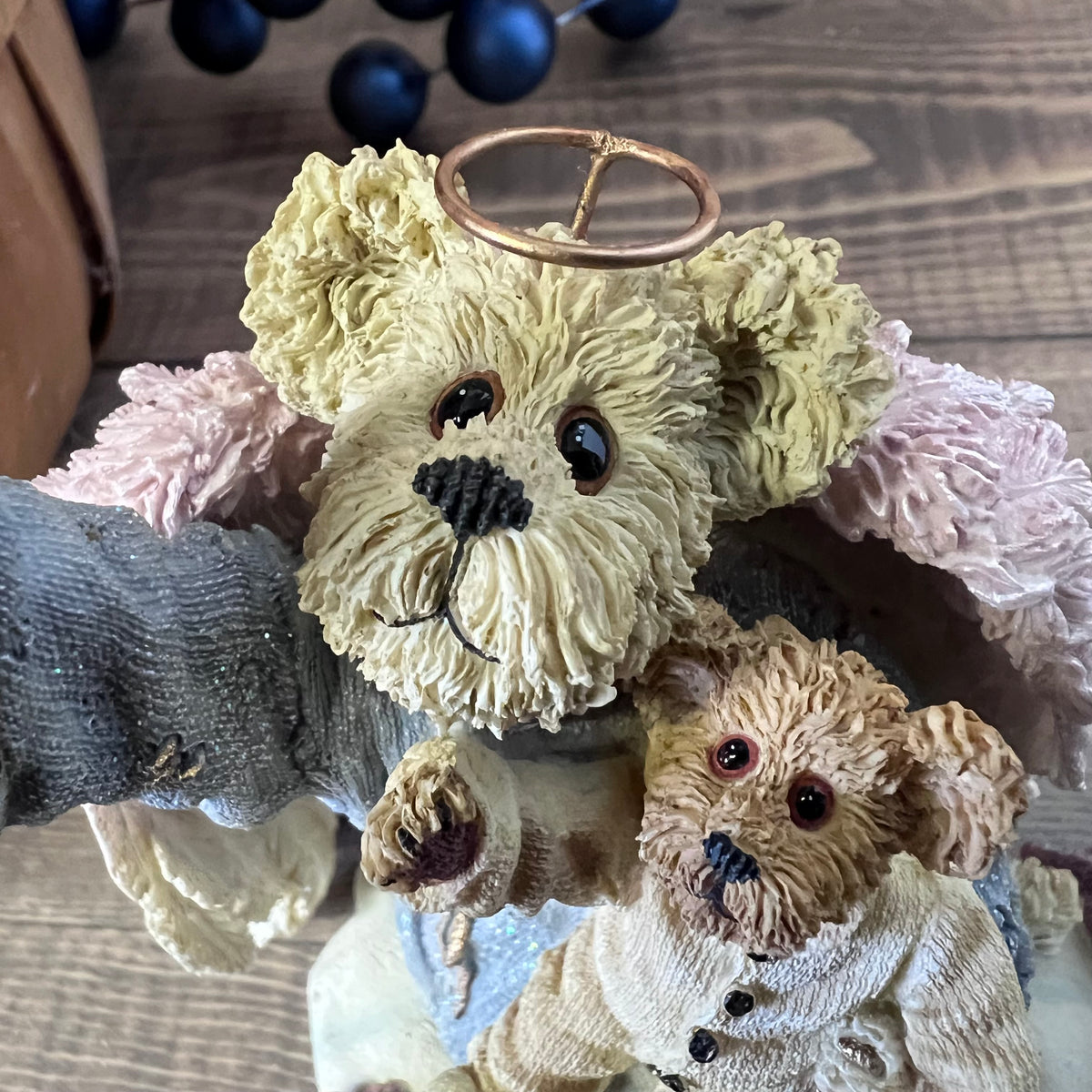 Two teddy bear figurines, one with a halo, on a textured surface.