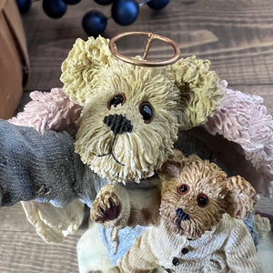 Two teddy bear figurines, one with a halo, on a textured surface.