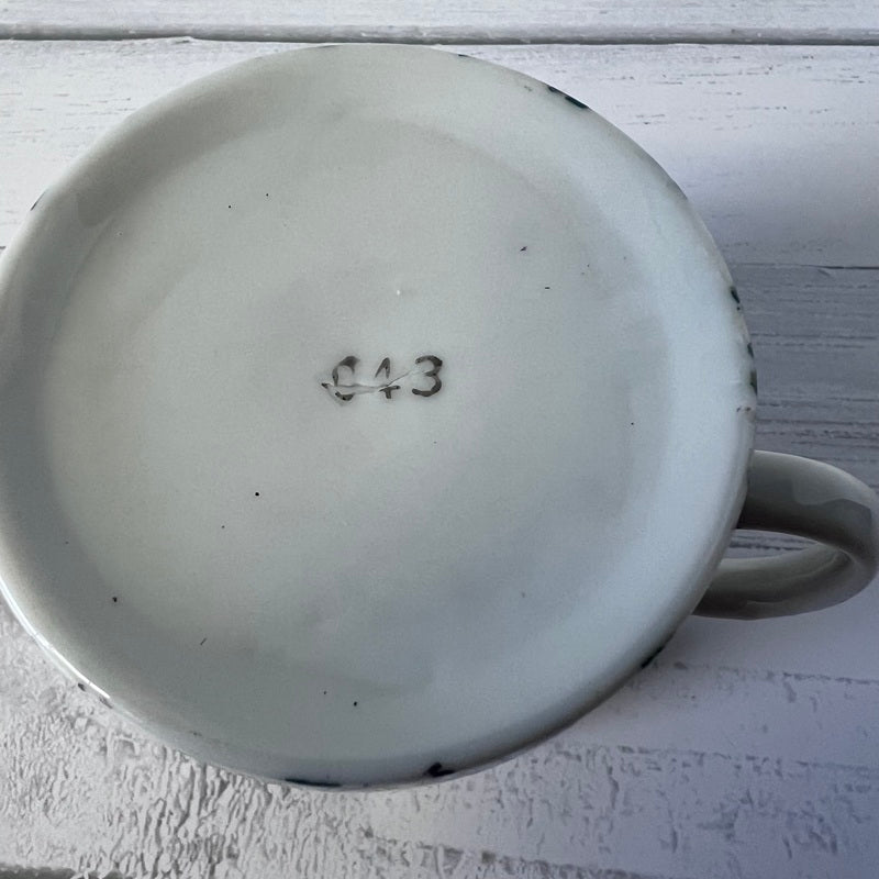 Ceramic mug with a number '043' on a light wooden surface