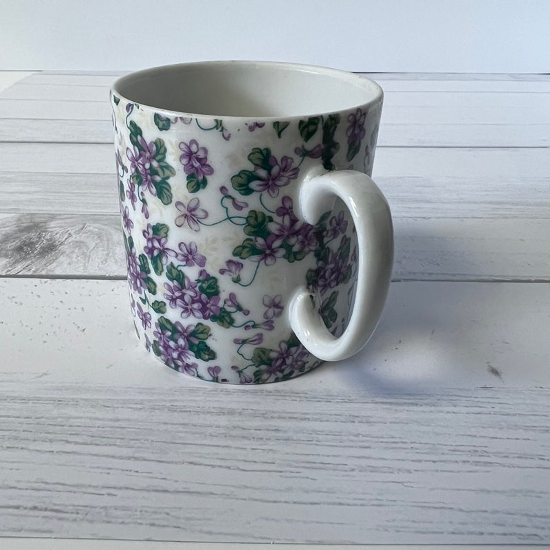 White mug with floral pattern on a light wooden surface