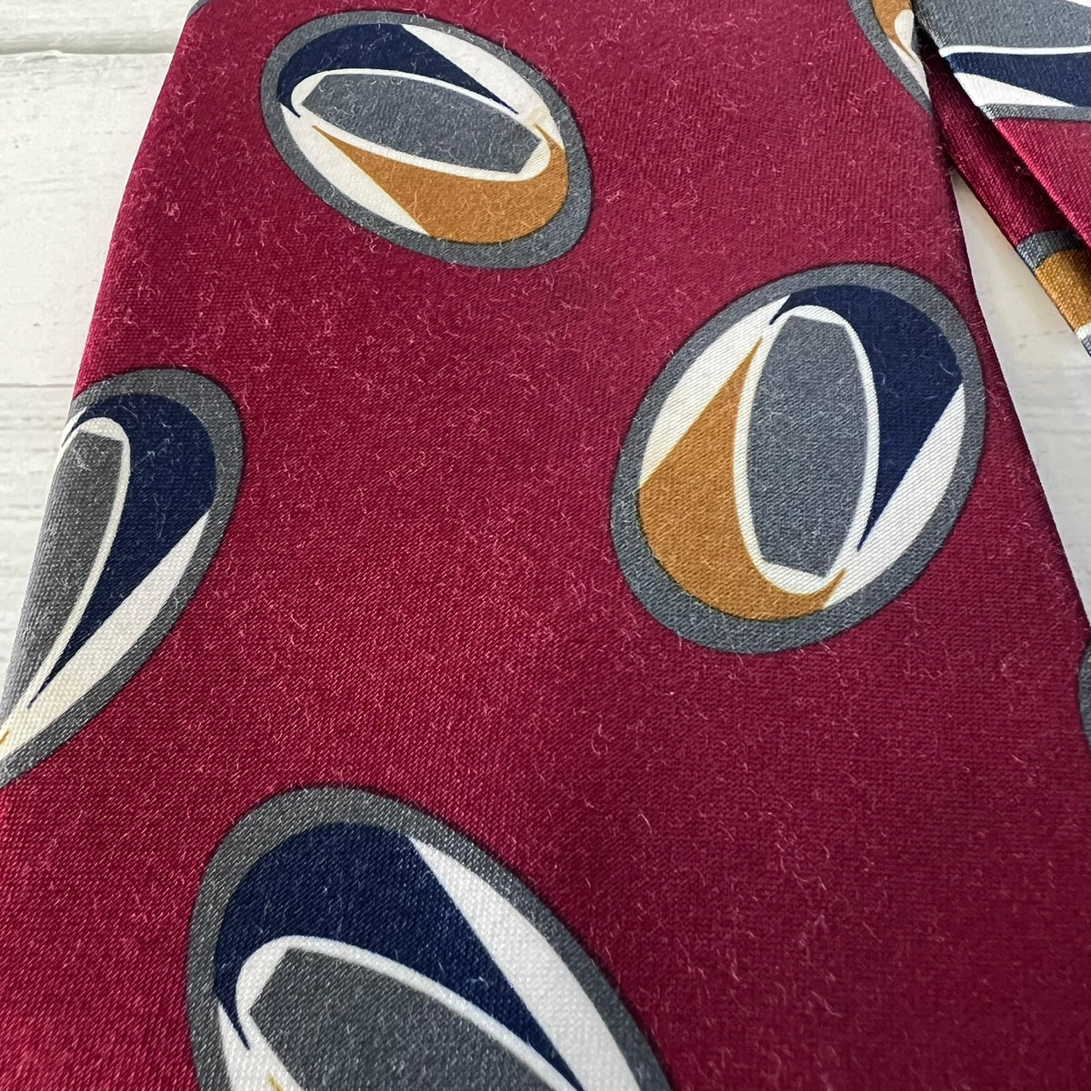 Close-up of a red fabric with circular patterns featuring blue, gold, and gray colors.