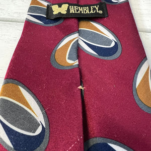 Maroon tie with multicolored circular patterns and 'Wembley' label on a wooden surface