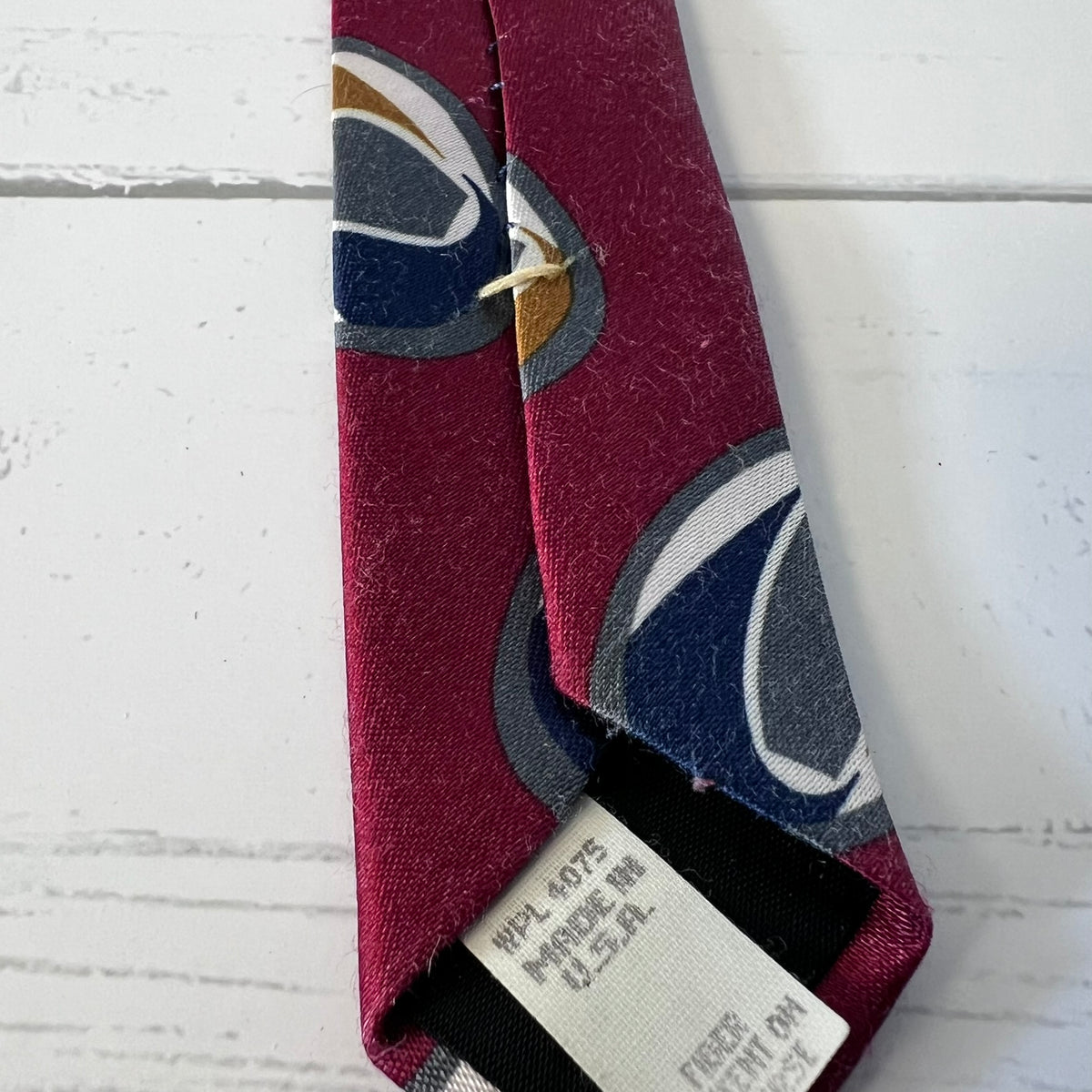 Maroon tie with abstract pattern on a white textured surface