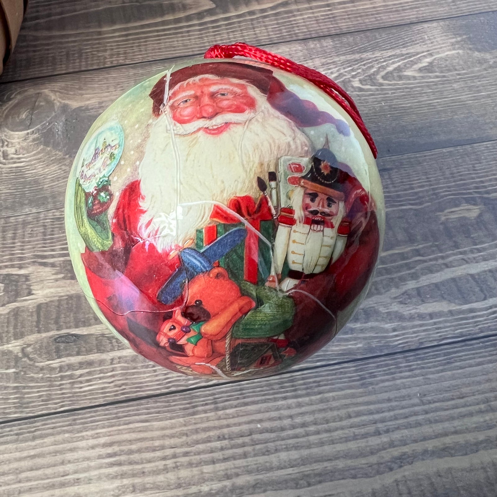Decorative Christmas ball with Santa Claus and nutcracker design on a wooden surface