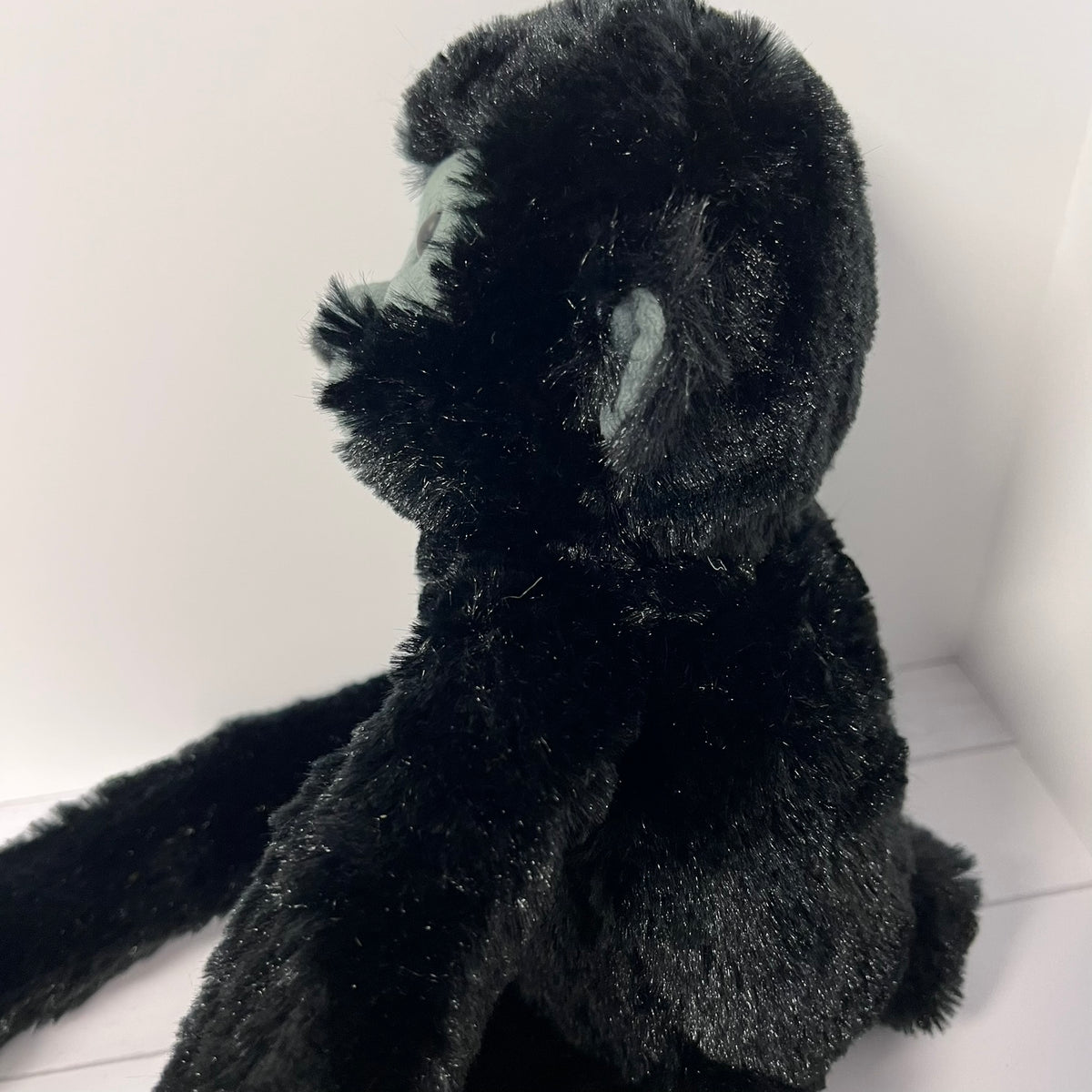Black plush monkey toy on a white floor