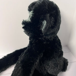 Black plush monkey toy on a white floor