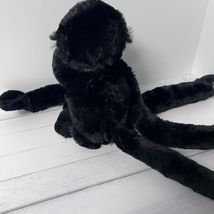 Black plush toy spider on a white wooden floor