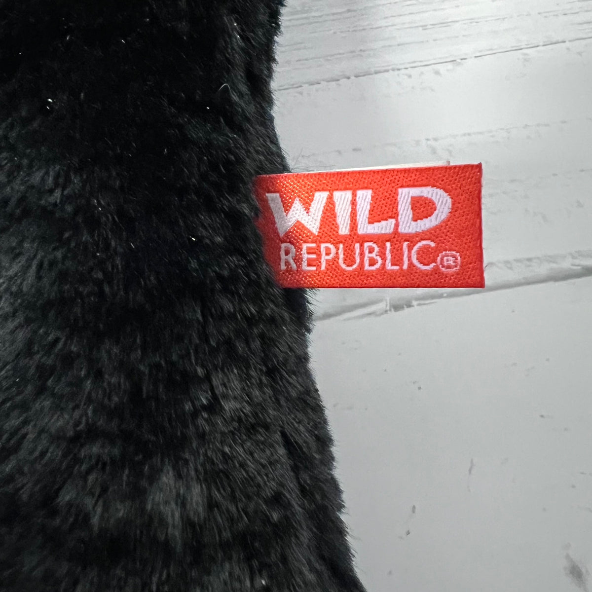 Black plush toy with a red 'Wild Republic' label on a light gray background