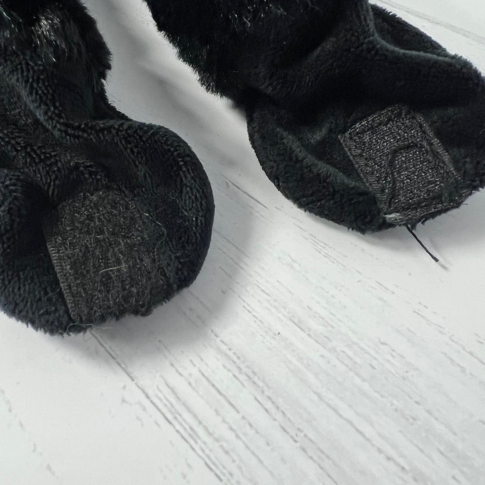 Black fuzzy socks on a light wooden floor