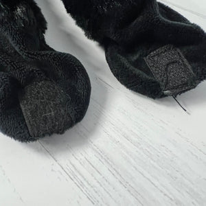 Black fuzzy socks on a light wooden floor