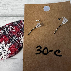 Pair of silver earrings on a brown card with '30-C' written on it, next to a red and white patterned object.