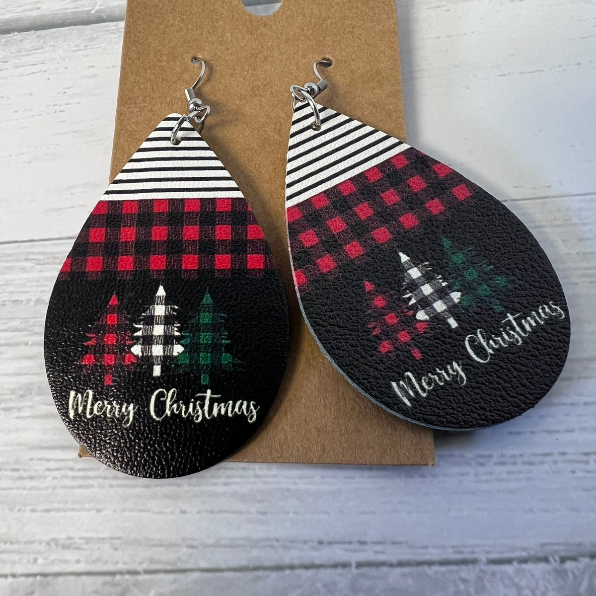 Teardrop-shaped earrings with Christmas designs on a cardboard backing.