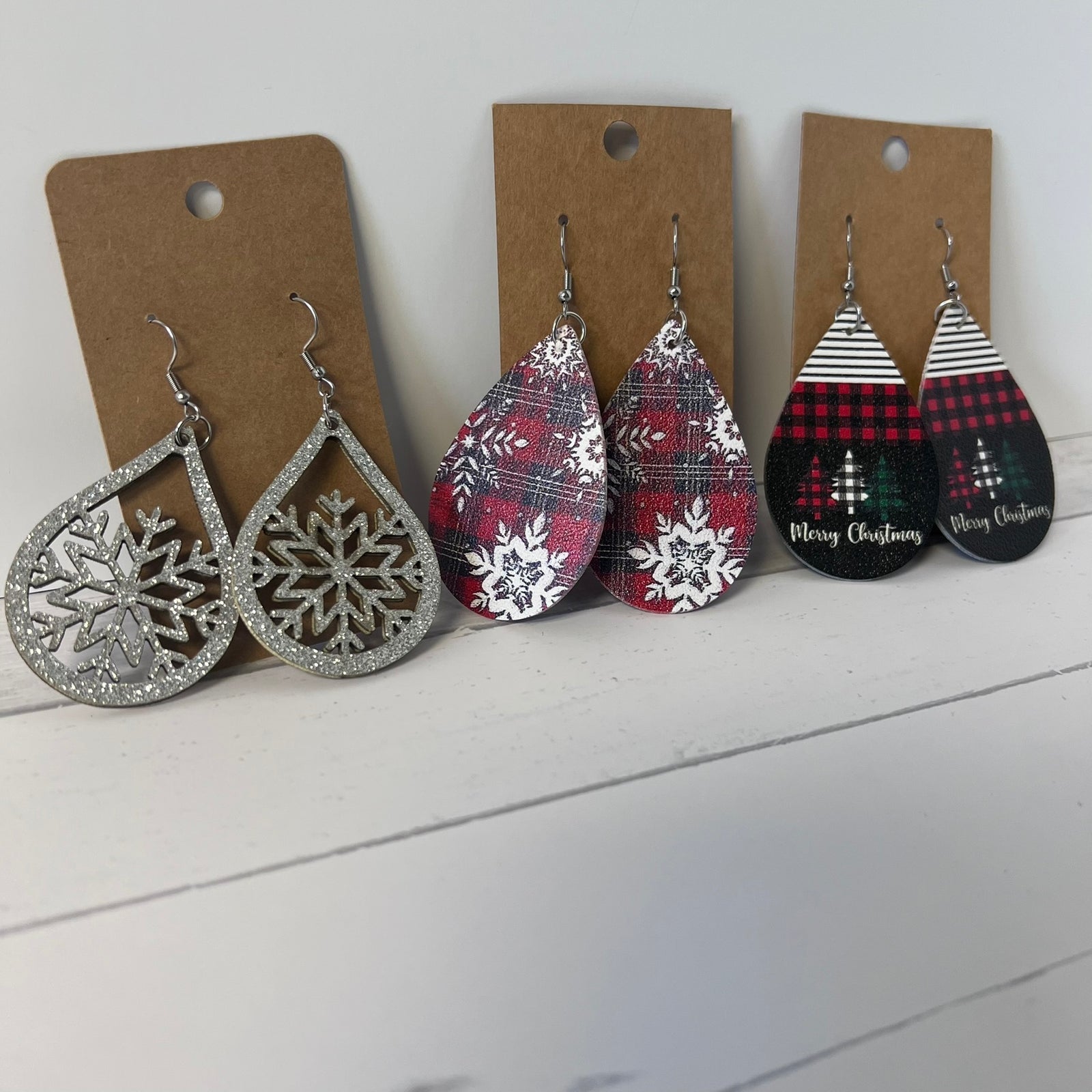Set of Christmas-themed earrings on brown cards against a white background