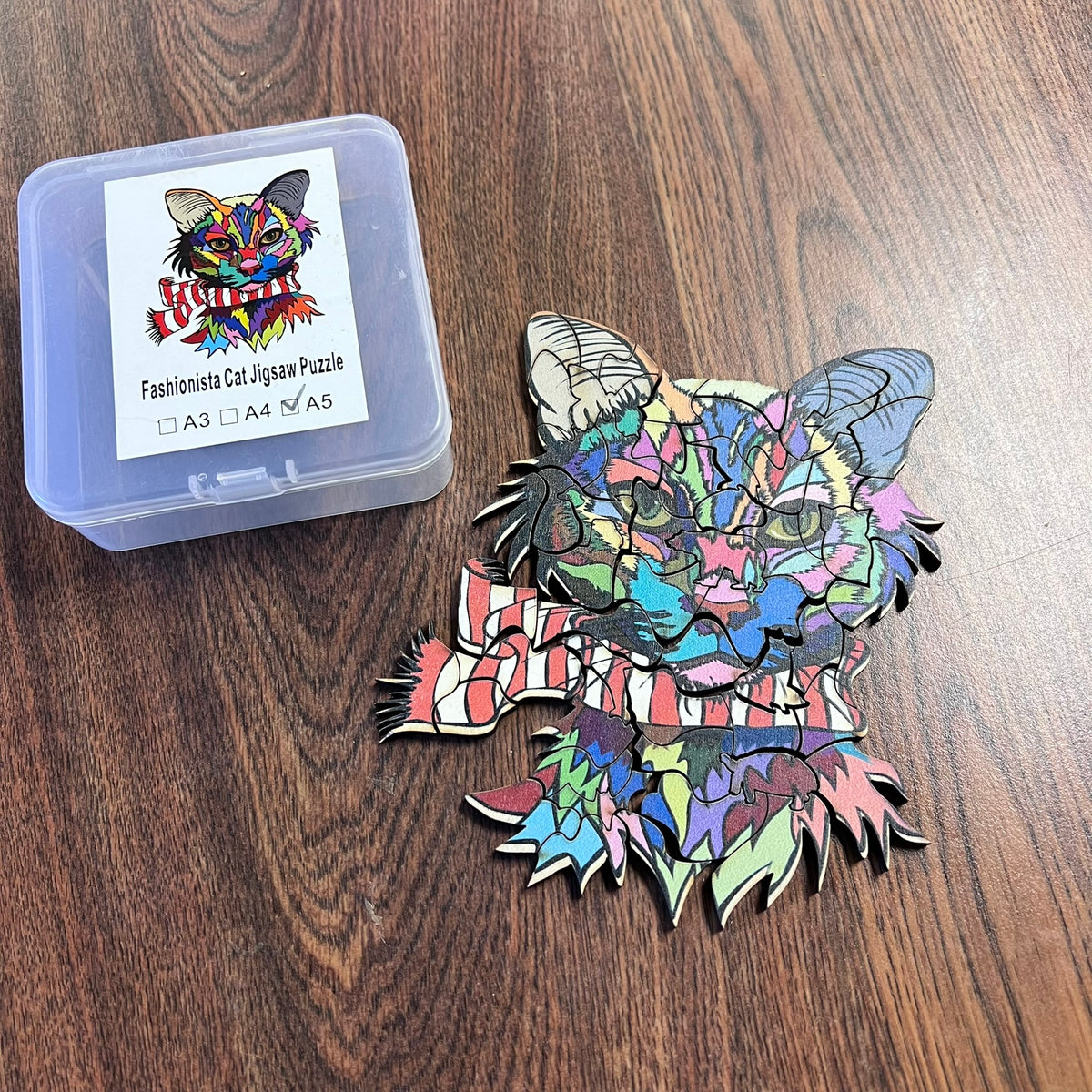 Colorful cat-shaped jigsaw puzzle piece on a wooden surface with packaging.