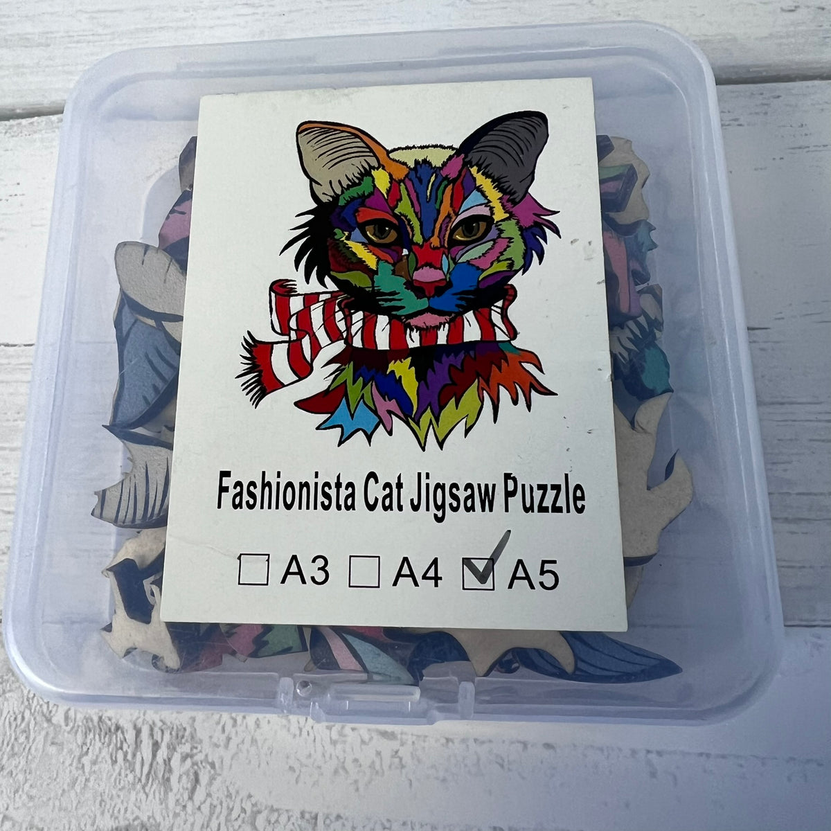Jigsaw puzzle packaging with a colorful cat illustration and size options.