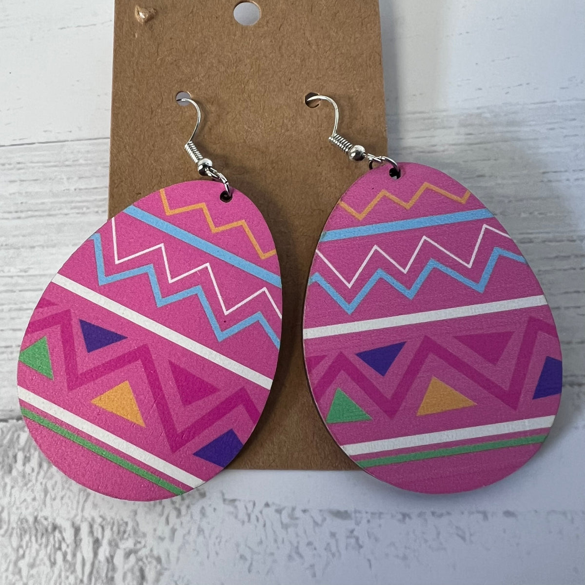 Pink geometric patterned earrings on a cardboard backing with a white background