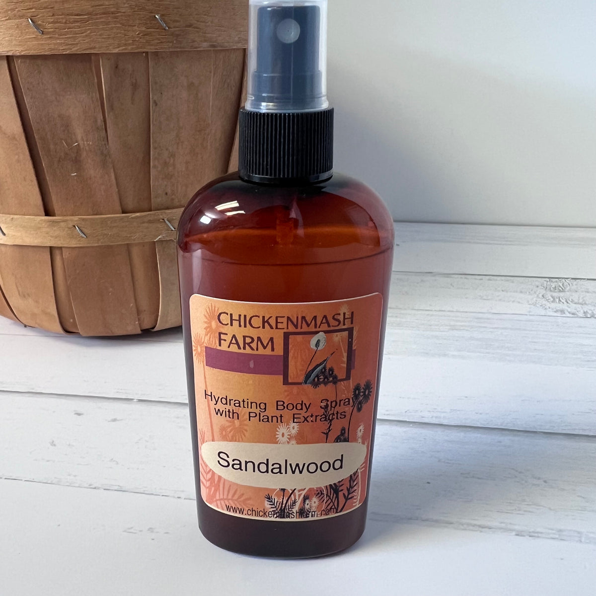 Bottle of Chickenmash Farm Sandalwood body spray on a wooden surface