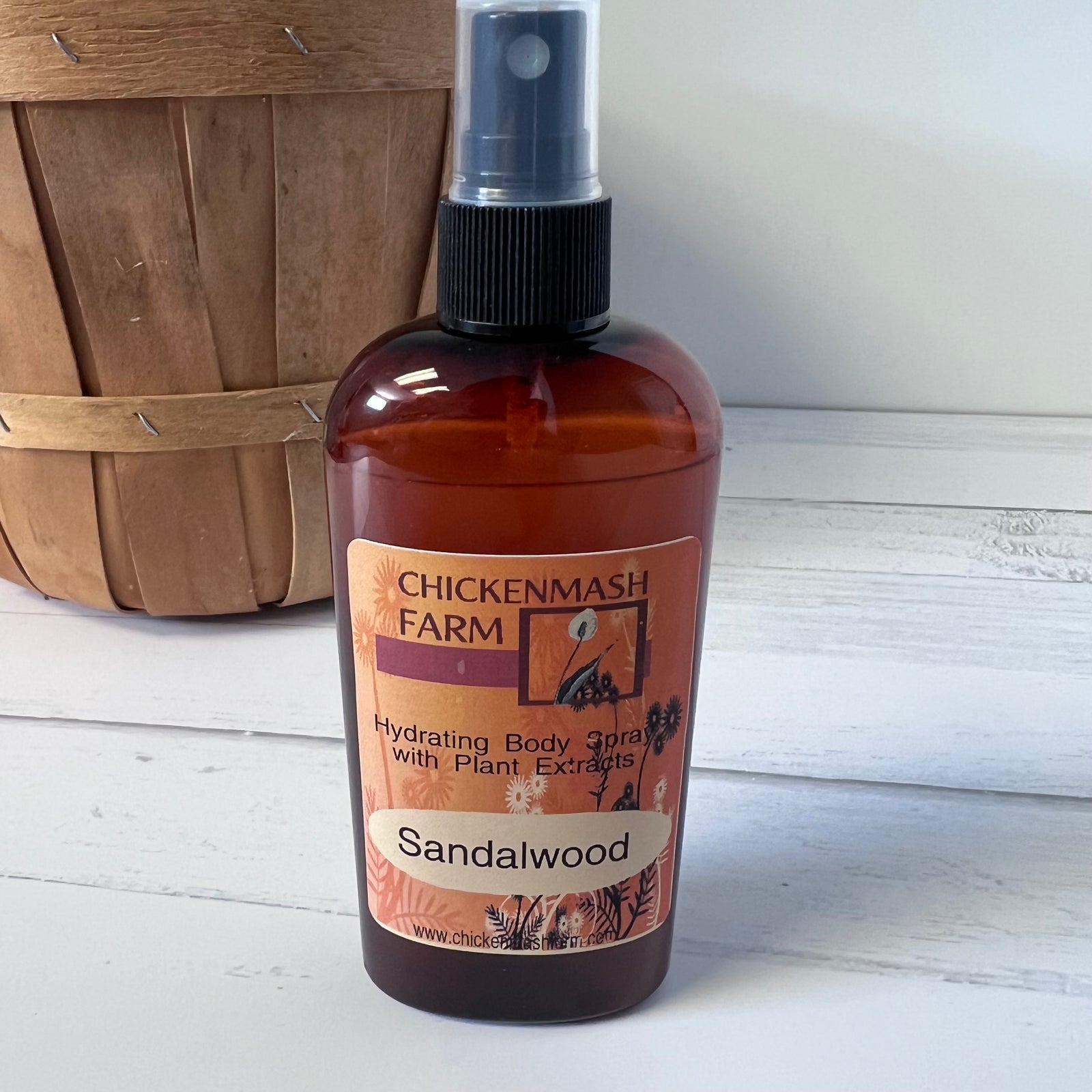 Bottle of Chickenmash Farm Sandalwood body spray on a wooden surface