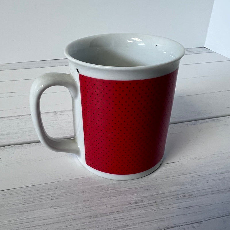 White mug with a red pattern on a white wooden surface